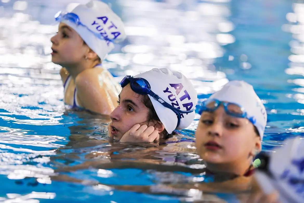 Ata boneli çocuklar havuzda eğitmenlerini dinliyor