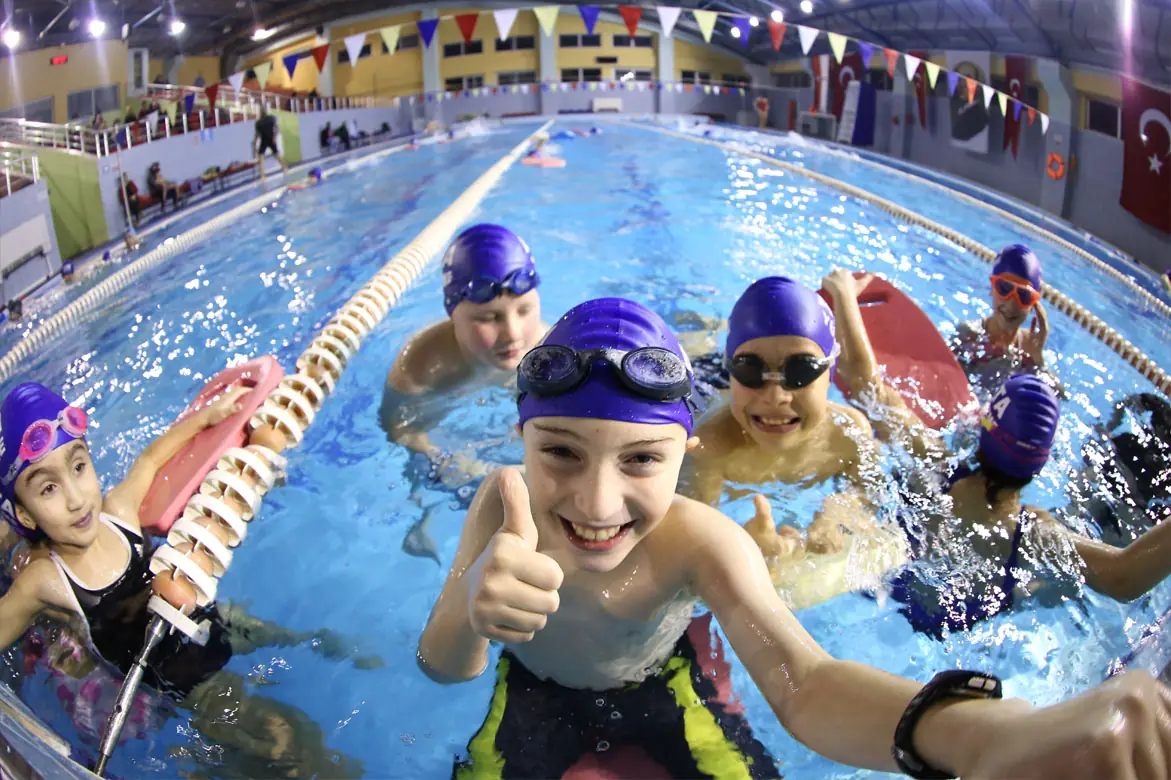 Children with Ata swim caps during training in the pool