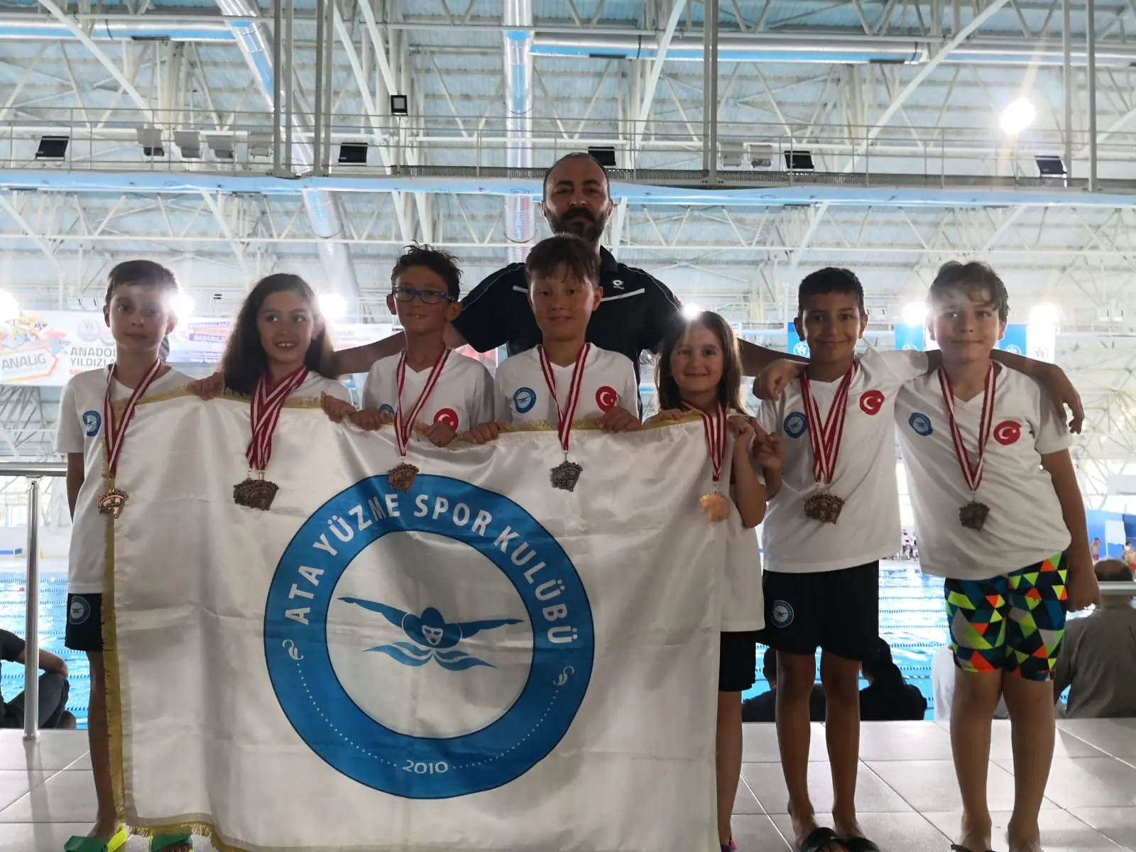 Medal-winning athletes and their coaches with the club flag