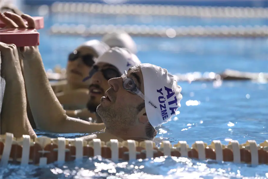 Adult swimming student at the laneside with his Ata swim cap